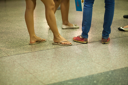Legs and feet of Thai woman wearing sandals  in MRT station in Bangkok
