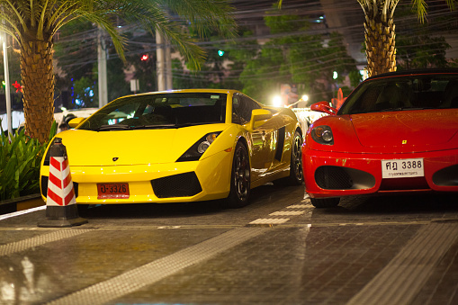 Red Porsche and yellow Ferrari are parked outside of hotel in Bangkok Ladprao