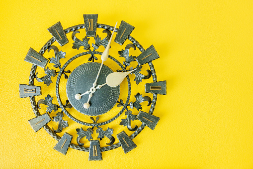 Time management, deadline and countdown concept : Vintage retro roman style / old antique clock on a yellow background with small space, depicts flowing or passing of time from past, present to future