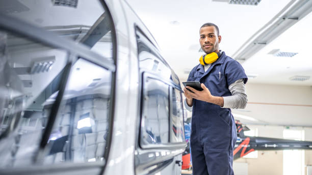 African American mechanic standing near jet and looking at camera, side view stock photo