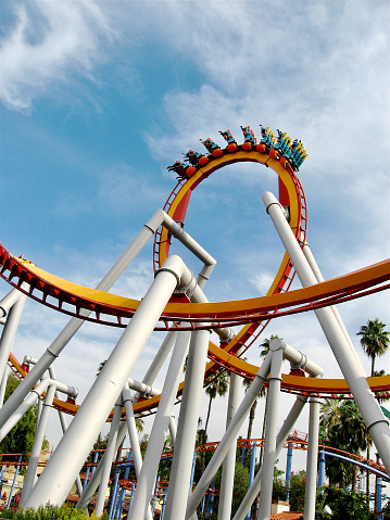 Low-angle wide shot of an inverted rollercoaster as the train goes over a loop against the sky