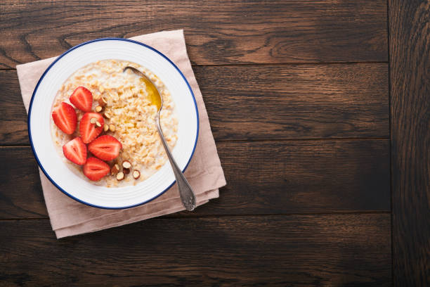 farinha de aveia. tigela de mingau de aveia com morango, amêndoa e leite no fundo da mesa escura de madeira velha. vista superior em estilo leigo plano. ingredientes naturais. café da manhã quente e saudável e comida dietética. - oatmeal heat bowl breakfast - fotografias e filmes do acervo