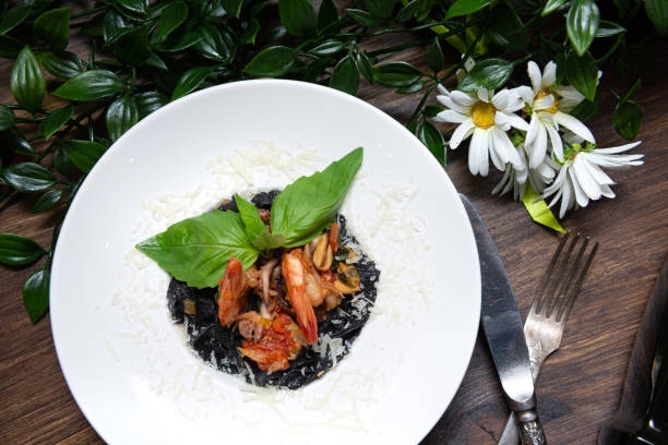black pasta with cuttlefish ink and seafood, under grated parmesan cheese, garnished with fresh basil leaves