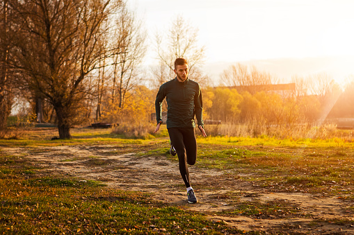 Young man runner athlete running in a park