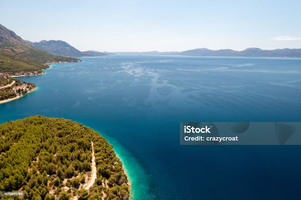 Large expanse of the coastline with a view towards the Pelješac peninsula with a large copy space in the photo The beautiful Adriatic coastline was photographed from a drone in Croatia, near the island of Hvar. Photo shows a range of colours from the white stones to turquoise and blues of the gorgeous Mediterranean Sea. Adriatic Sea Stock Photo