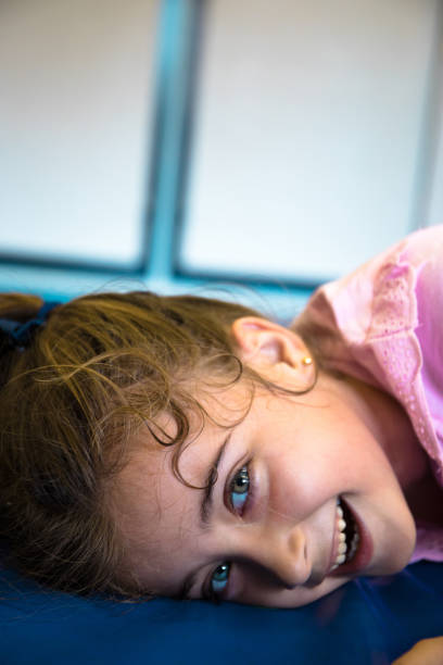 istock School student girl with blue eyes, playing and lying on the gym mat while smiling. 1410691806