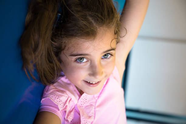 School student girl with blue eyes, playing and lying on the gym mat while smiling. Back to school