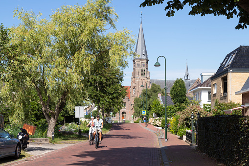 Reeuwijk-Dorp, Netherlands, July 24, 2022; Street in the rural village of Reeuwijk-Dorp with the Sint-Petrus en Pauluskerk in the background.