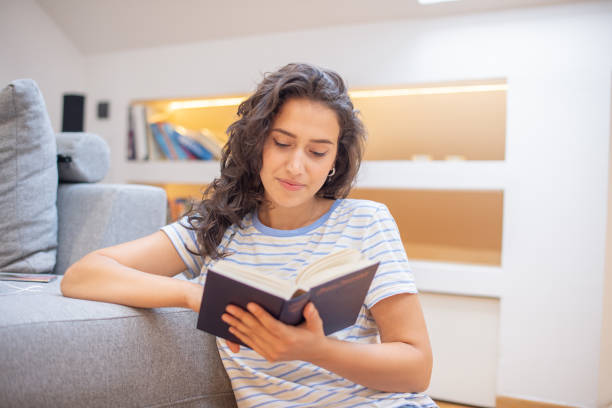 istock Happy woman reading book at home 1410709120