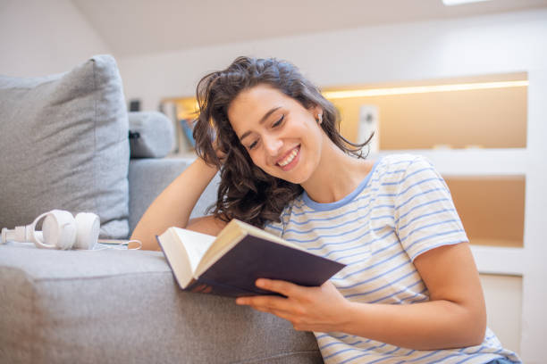istock Happy woman reading book at home 1410709122