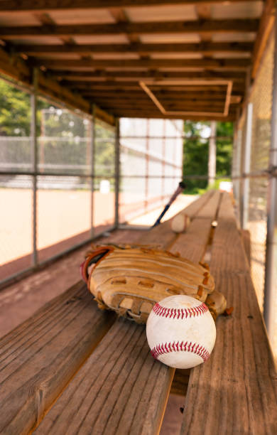 istock Baseball with glove on dugout bench with blurred background 1410711600