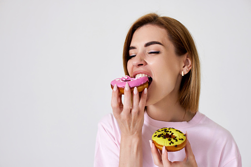 smiling beautiful blonde woman eating donuts isolated on white background. copy space