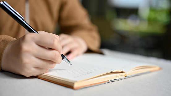 Una estudiante universitaria escribiendo su tarea en un cuaderno escolar. Primer plano y mano de enfoque photo