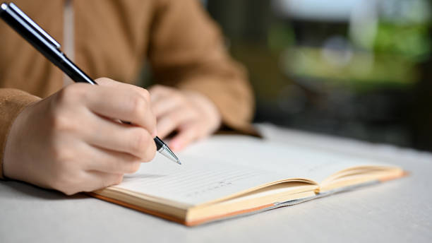 A female college student writing her homework on a school notebook. Close-up and focus hand stock photo