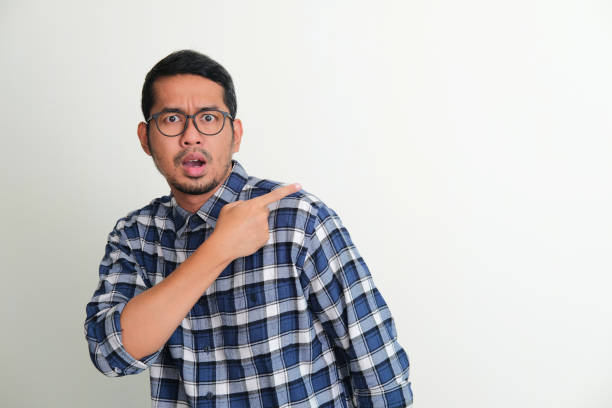 istock Adult Asian man looking camera with worried expression while pointing behind 1410731929