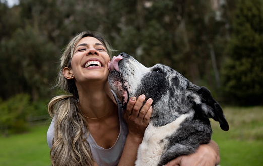 Happy Latin American woman playing with her dog outdoors - pets concepts