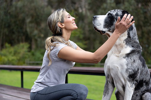 Happy Latin American woman pampering her dog outdoors - pets concepts