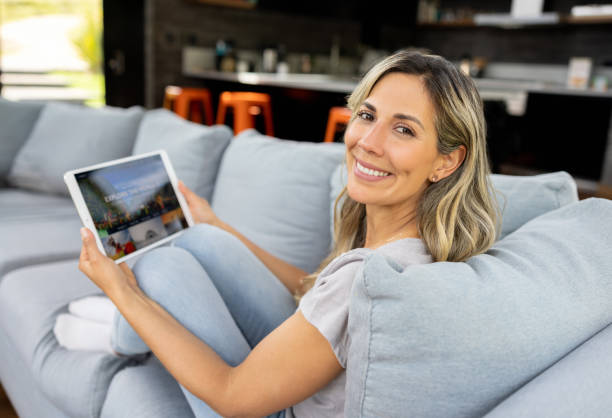 istock Happy woman at home booking a trip online using her tablet 1410734321
