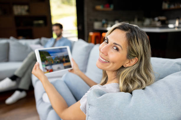 istock Happy woman at home booking a trip online using her tablet 1410734330