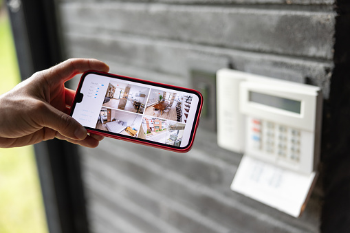 Close-up on a man watching the security cameras of her house in her cell phone â home automation concepts