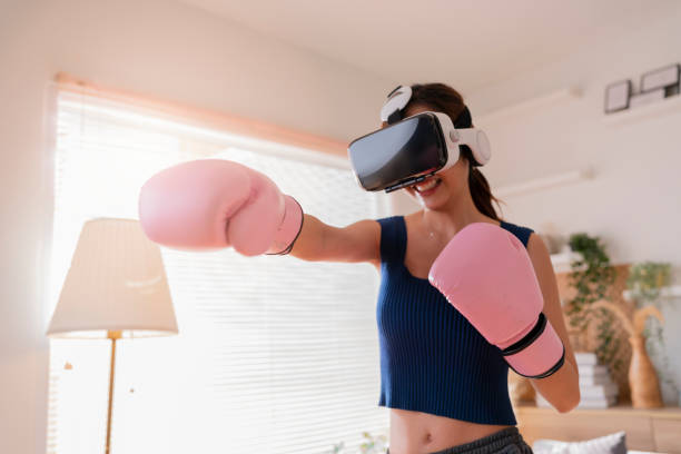 Virtual Metaverse Augmented Reality asian female adult working out boxing in VR headset aerobic training for boxing punch in virtual reality at living room home interior background Virtual Metaverse Augmented Reality asian female adult working out boxing in VR headset aerobic training for boxing punch in virtual reality at living room home interior background boxercise stock pictures, royalty-free photos & images