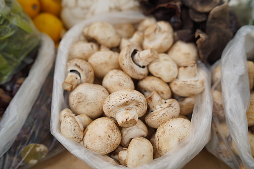 Champignon Mushroom or Jamur Kancing in plastic at traditional market. Selective focus