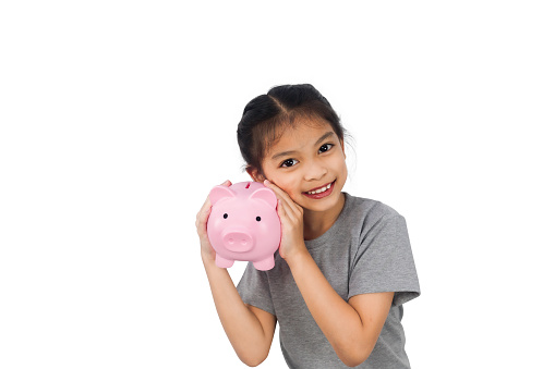 A child girl with a pink piggy bank isolated on white background.