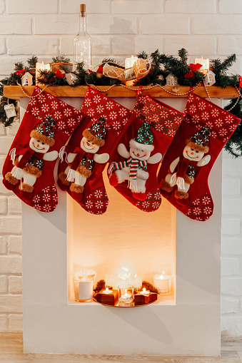Four Christmas red socks hanging on white fireplace in room