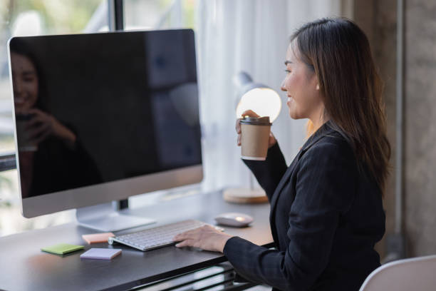 istock Smiling Asian woman drinking coffee while working online from home 1410751874