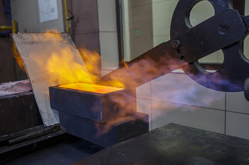 Pouring hot liquid gold into molds. Copper foundry workshop.