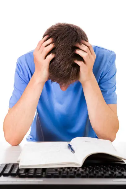 Sad Young Man with a Book and a Computer Keyboard on the White Background