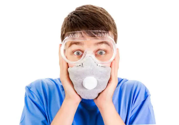 Shocked Young Man in a Gas Mask and in a Safety Glasses Isolated on the White