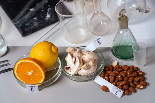 Oranges, mushrooms and nuts on a laboratory table with vitamin names. Essential vitamins. Food test laboratory.