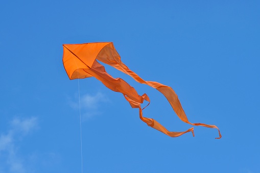 Orange kite against blue sky