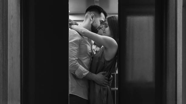 Young stylish caucasian couple hugging and kissing in hotels elevator stock photo