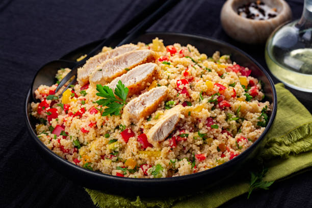 Couscous salad with Chicken breast and vegetables, tomatoes, avocado, bell pepper, parsley and lemon juice. Black table surface. Close-up. stock photo