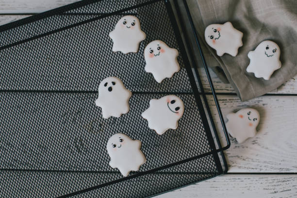 istock Funny scary Halloween ghost cookies with white icing on black tray. 1410764034