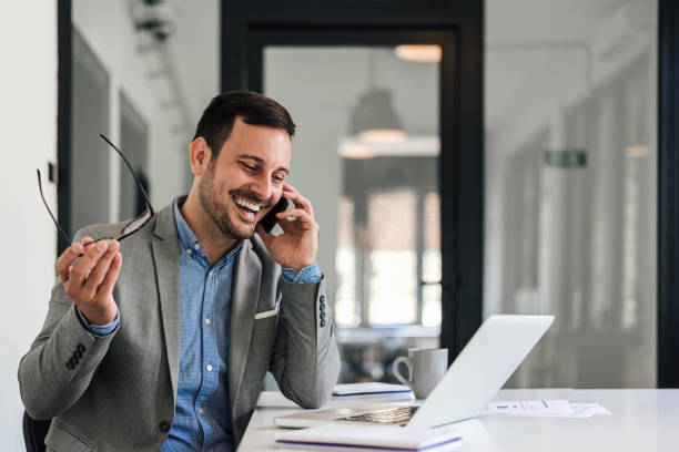 istock Happy businessman talking on smart phone while sitting at desk in office. 1410764121