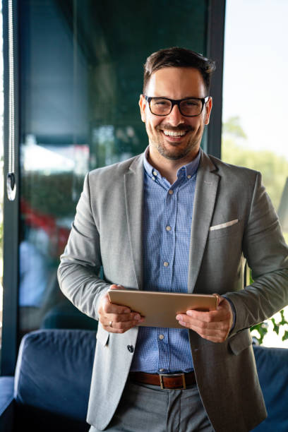 Portrait of happy succeffsul young business man, leader, ceo, manager using digital tablet to work. stock photo