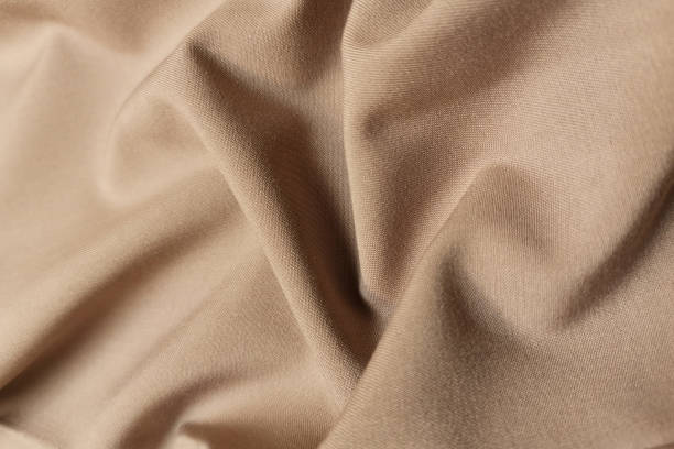 istock Beige or sand crumpled or wavy fabric texture background. Abstract linen cloth soft waves. Silk atlas or stretch jacquard. Smooth elegant luxury cloth texture. Concept for banner or advertisement 1410766079