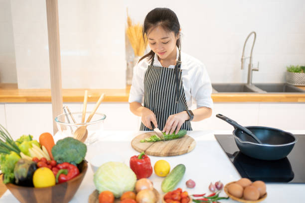 istock Attractive asian woman cutting cucumber at kitchen 1410768454
