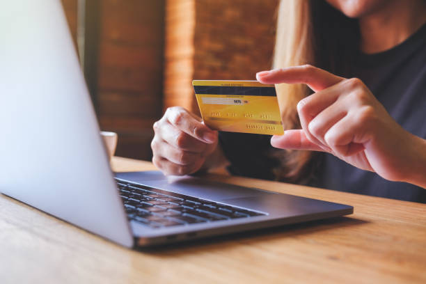 istock Closeup image of a woman holding credit cards while using laptop computer for online payment 1410771041