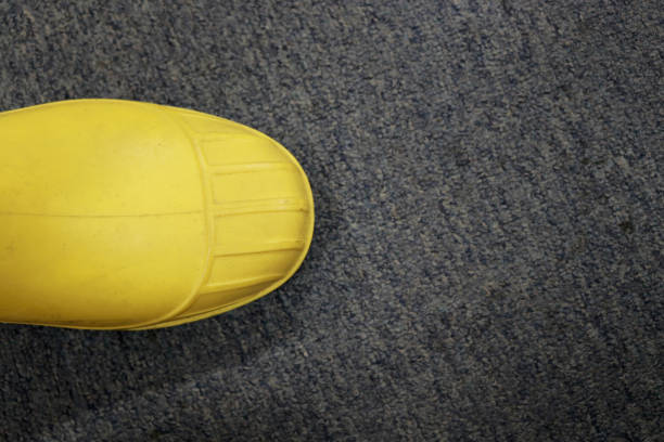 Yellow rubber boots that are waterproof are usually worn by construction workers, to protect their feet from work accidents, such as impact of hard objects, chemicals, toxic liquids, floods and othe