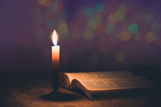 Candle with bible on a old oak wooden table. stock photo