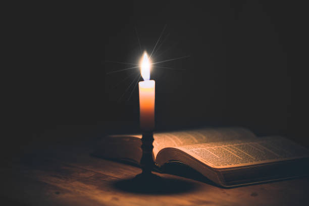 istock Candle with bible on a old oak wooden table. 1410773073