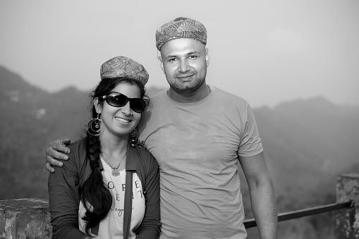Young couple of Indian ethnicity standing against mountain background in Himachal Pradesh, India.