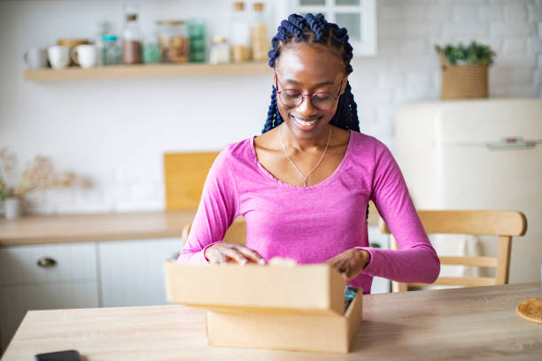 istock Young Black Woman Receiving Box And Unpacking It 1410774374