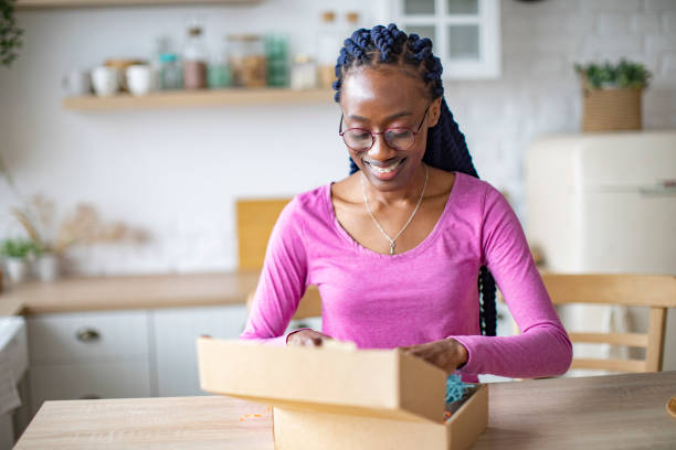 istock Young Black Woman Receiving Box And Unpacking It 1410774375