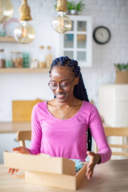 istock Young Black Woman Receiving Box And Unpacking It 1410774428