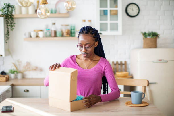 istock Young Black Woman Receiving Box And Unpacking It 1410774449
